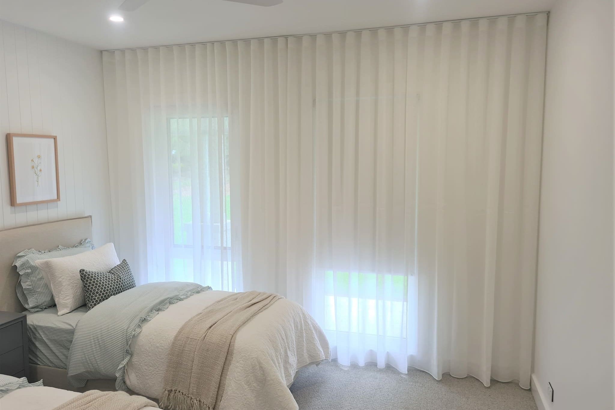 Floor to ceiling sheer curtains across a bedroom wall