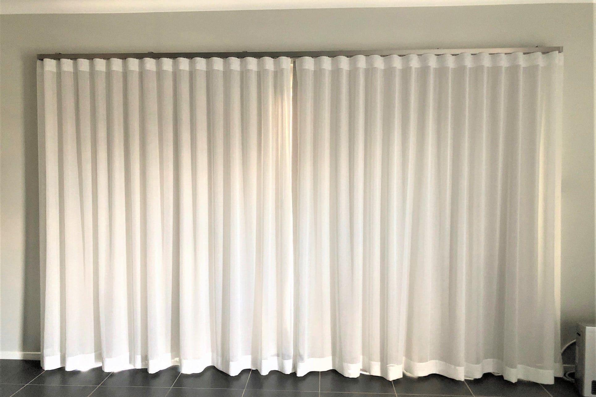 S-fold sheer curtains hanging from a ceiling-mounted track